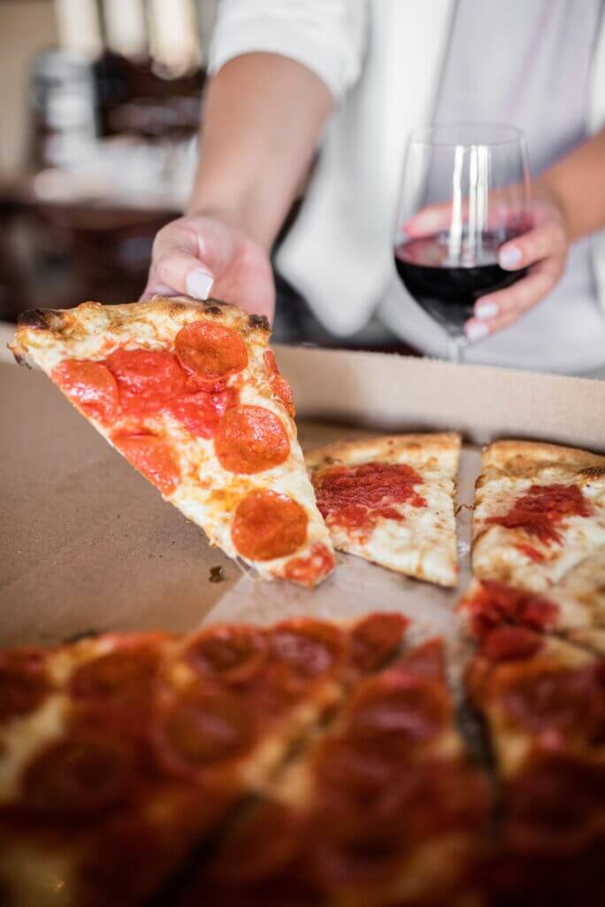 glass of wine with a slice of pizza