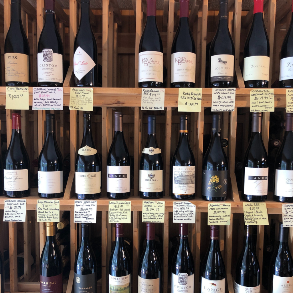 different types of wine on a shelf in a store with descriptions on a label below each