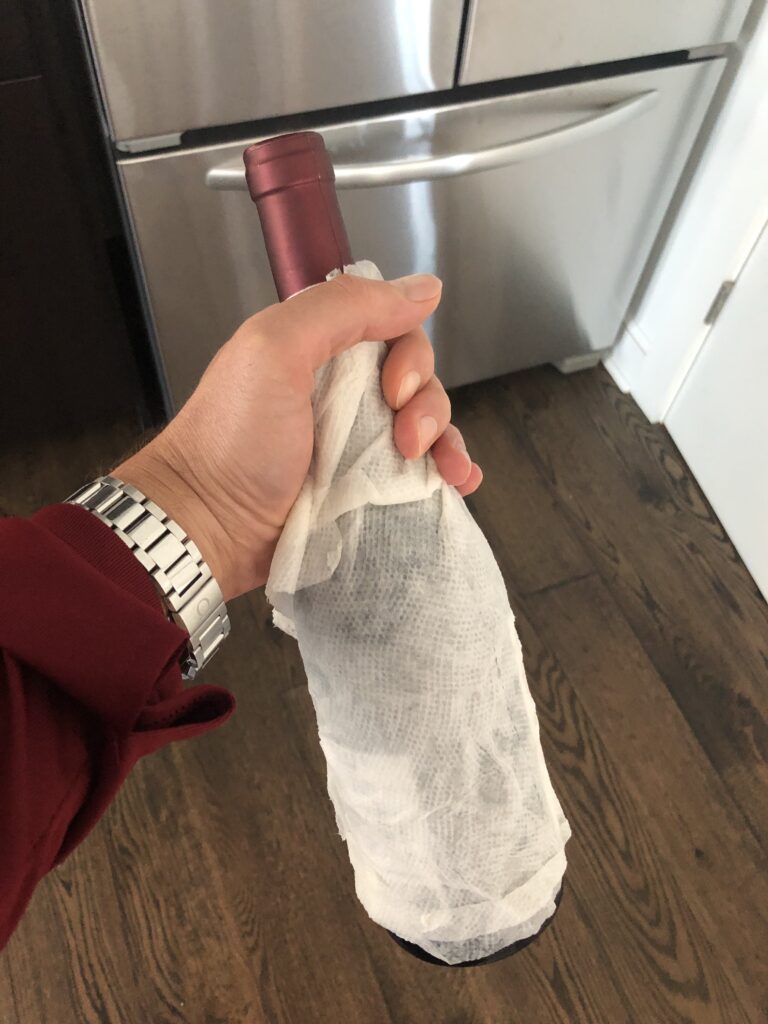wet paper towel wrapped around a bottle of wine headed to freezer